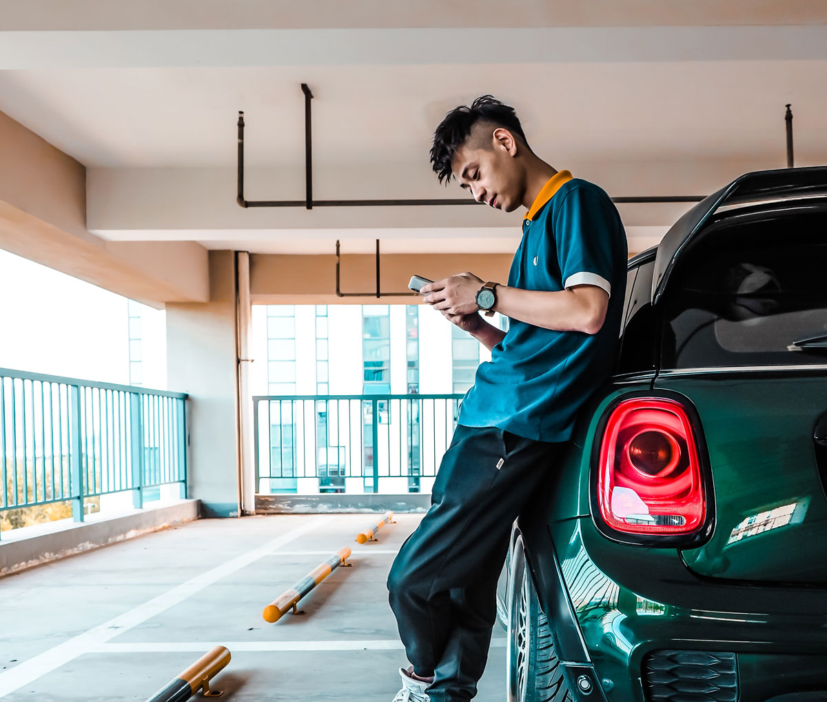 A man using his phone and leaning on his car