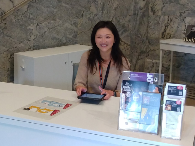 a woman sitting at a registration desk in the museum lobby