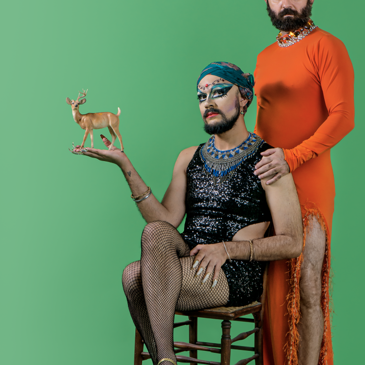 two men in women's clothing standing before a green background