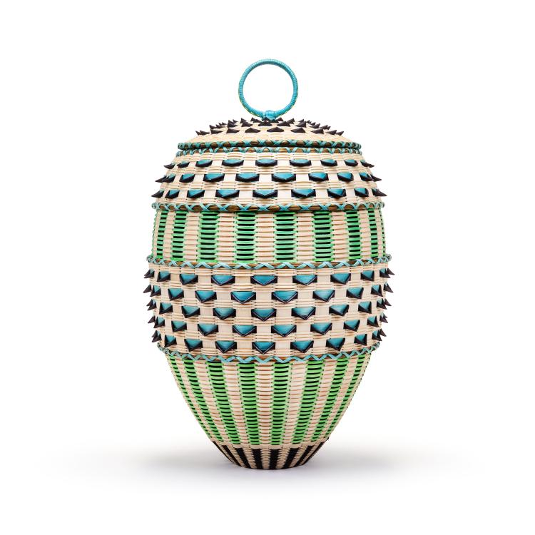 An intricately woven oval basket with a lid and top ring handle, featuring alternating bands of cream, bright green, and turquoise elements with protruding dark points against a plain white background.