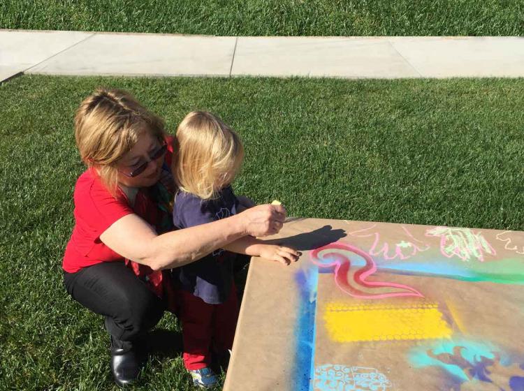 A woman and a child making art on the grass with the legend Art for All Family Days