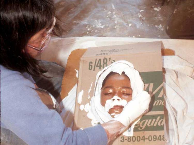 A color image of Ruth Asawa casting a student's face in plaster from 1982. 
