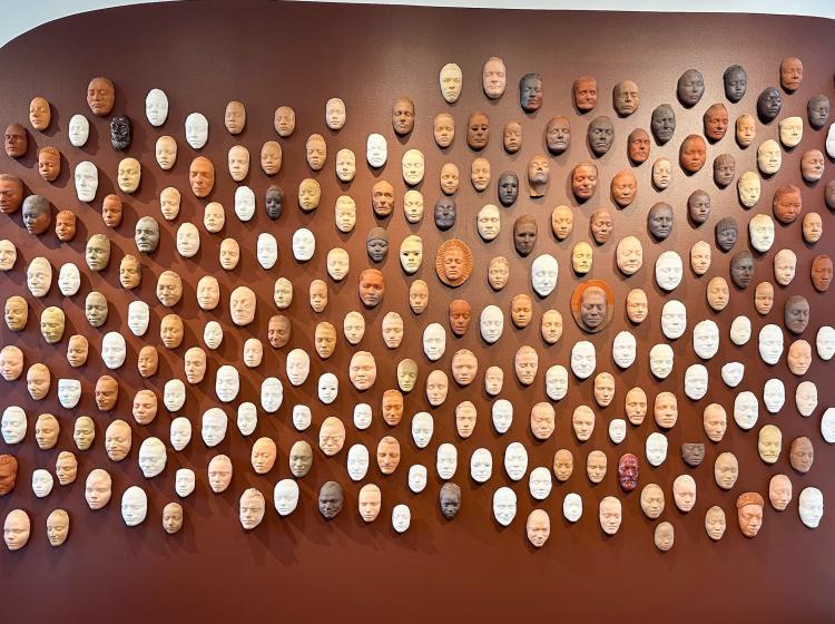 a wall covered in masks made of clay
