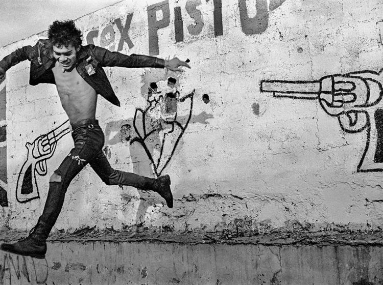 An image of a man jumping behind a wall with a pistol drawn on it