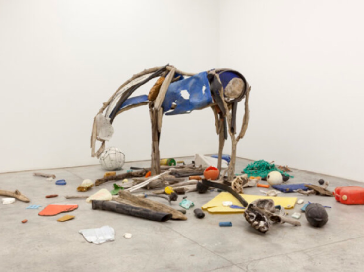 an installation shot of Convergence Zone, depicting a horse and some trash strewn across simulating a beach