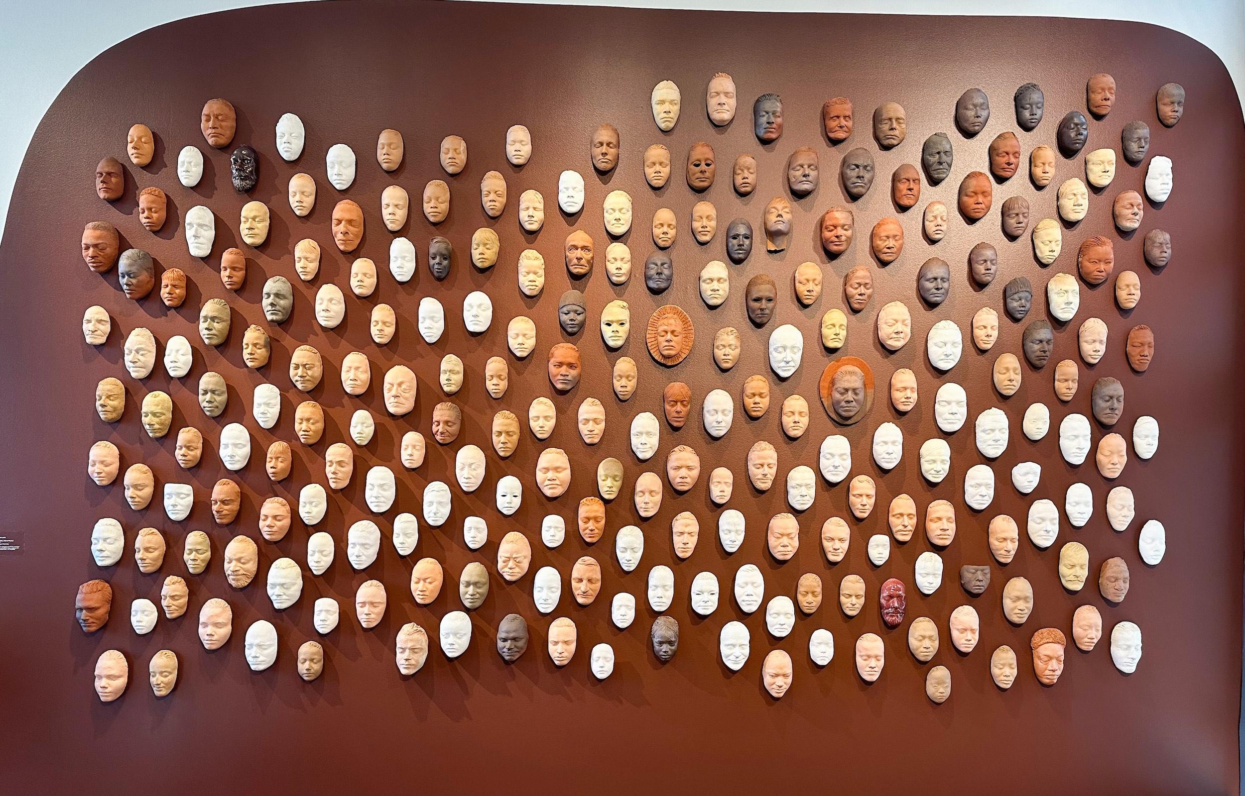 a wall covered in masks made of clay