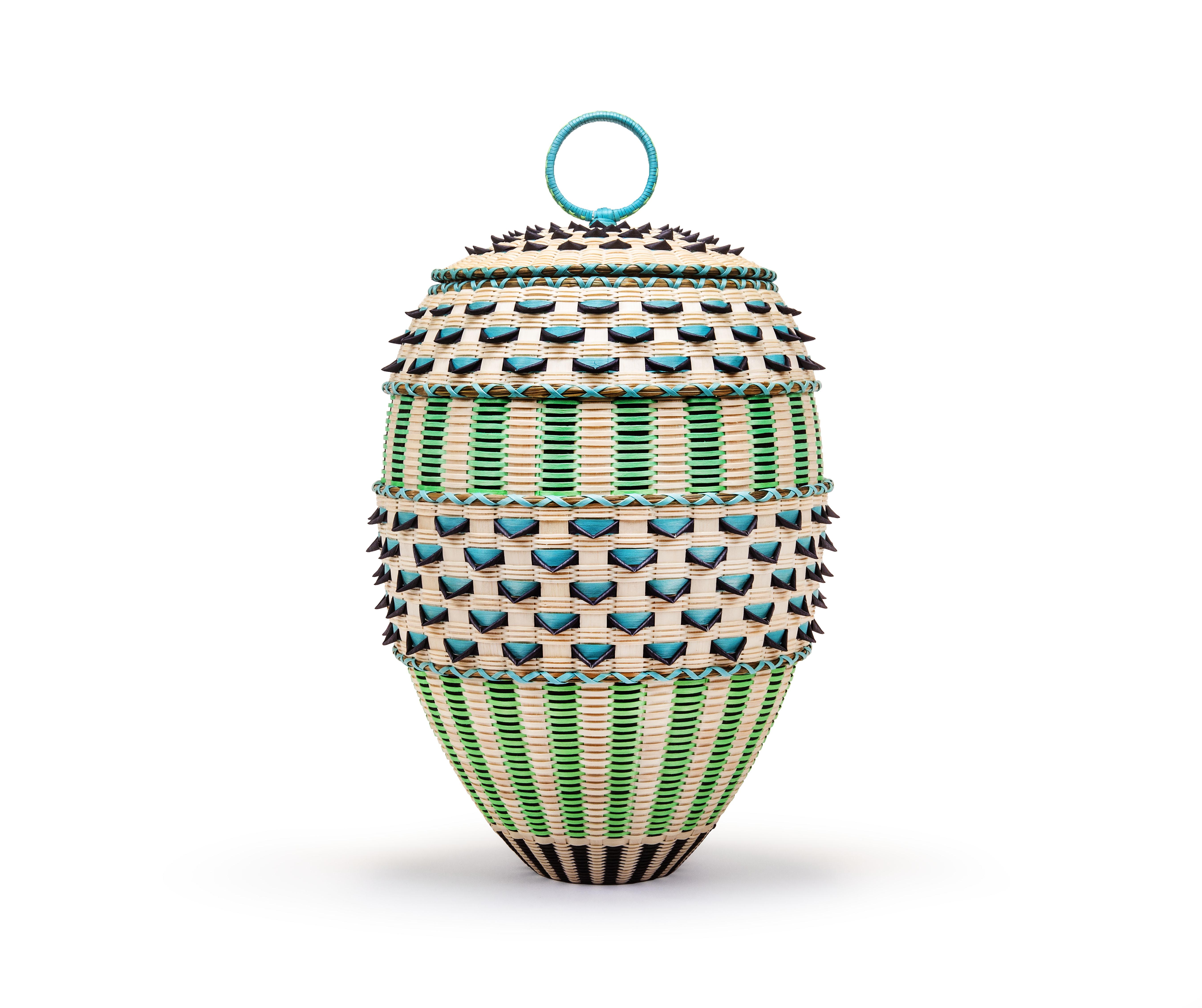 An intricately woven oval basket with a lid and top ring handle, featuring alternating bands of cream, bright green, and turquoise elements with protruding dark points against a plain white background.